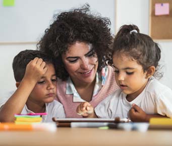 preschool teacher and children at a table