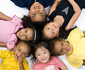 Six happy preschool students laying in a circle