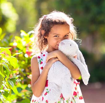 little girl outside holding a bunny toy